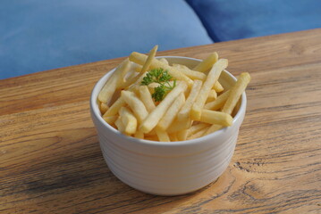 Close up of  french fries in a bowl on a wooden desk