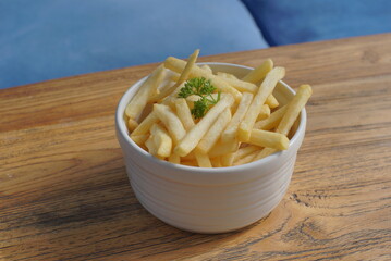 Close up of  french fries in a bowl on a wooden desk