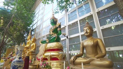 The Buddha statue is carved from green jade stone and decorated with gold. - Powered by Adobe