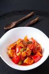 Asian food concept sweet and sour Chicken in white ceramic dish on black slate stone background
