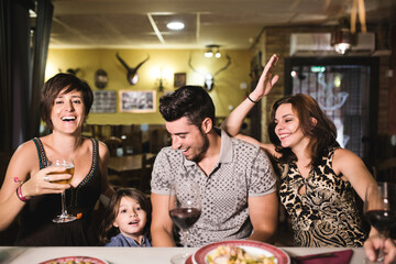 Group of friends having dinner in restaurant bar with children