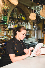 Waitress in bar with tablet looking orders
