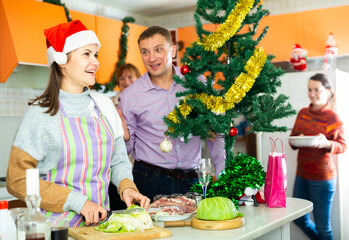 Happy family preparing for celebration of New Year, young woman making salad