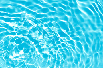 Blurred transparent blue colored clear calm water surface texture with splashes and bubbles. Trendy abstract nature background. Water waves in sunlight with copy space.