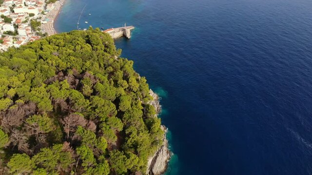 Aerial view by the rocky coas Adriatic sea t in Montenegro. Large trees, pines in the foreground. In the background you can see the bay with the city.