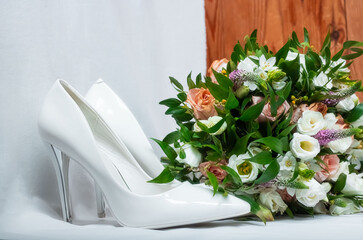 Bridal bouquet and white wedding shoes on a light background.
