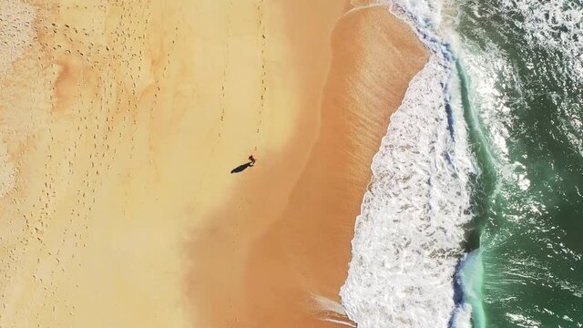 Overhead Aerial View Of a man walking alone on empty beach
