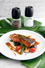 Teriyaki salmon on black background. Japanese cuisine inspired dinner consisting of grilled salmon fillet glazed in delicious teriyaki sauce (soy sauce base). Brussel sprouts and white rice as sides.