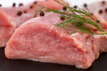 raw pork tenderloin with herbs on a black tray