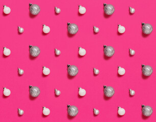 Silver and white Christmas baubles on a pink background