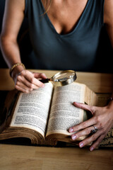 The women is reading a book through the magnifying glass