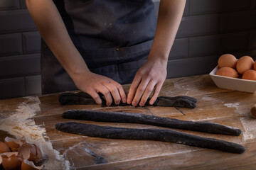 Chef preparing a portion of fresh dough with sepia addition for black dumplings. Cooking dumplings – step by step guide.