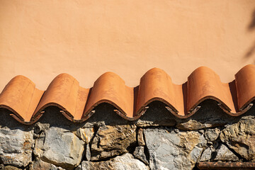 Closeup of a stone surrounding wall with roof tiles made of terracotta, Liguria, Italy, southern Europe
