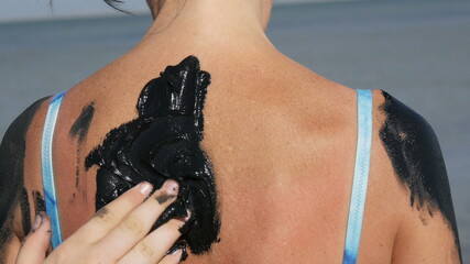 Healing black medical mud applies on back woman at the lake of salt water. Salty black dirt Is good...