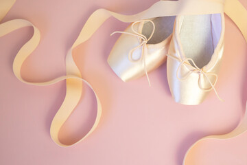 Romantic background. Pink ballet pointe shoes with ribbons on pink background. Place for text. Top view.