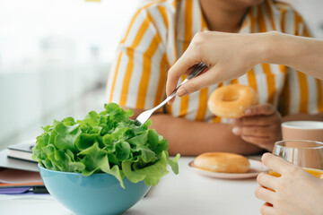 Woman eating healthy food salad vegetables with fork for lunch.