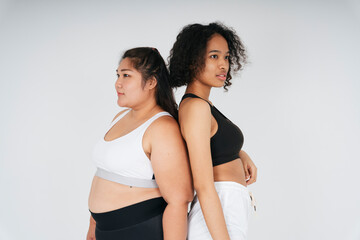 Fototapeta na wymiar Diverse women with chubby asian and african woman in sportbra over white background.