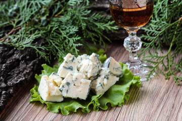 Cheese with mold on lettuce leaves with a stack of acogola on a wooden background.