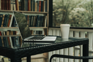 there is a laptop and a mug with coffee on the table in the autumn park. There is a bookcase next...