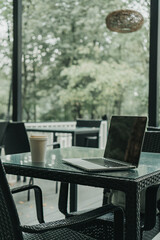 there is a laptop and a glass of coffee on the table in a cafe in the park