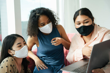 Three diverse women wear mask doing streaming with computer laptop at home.