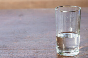 A glass of fresh drinking water on a wooden table.