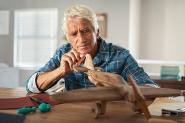 Old man perfecting a handmade wooden plane