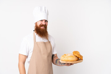 Redhead man in chef uniform. Male baker holding a table with several breads smiling a lot