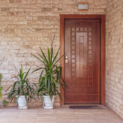 Fototapeta na wymiar contemporary stonewall house with wooden entrance door and flowerplants, Athens Greece