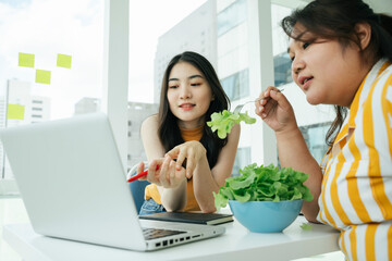 Asian women eating healthy food for lunch and looking at laptop computer.