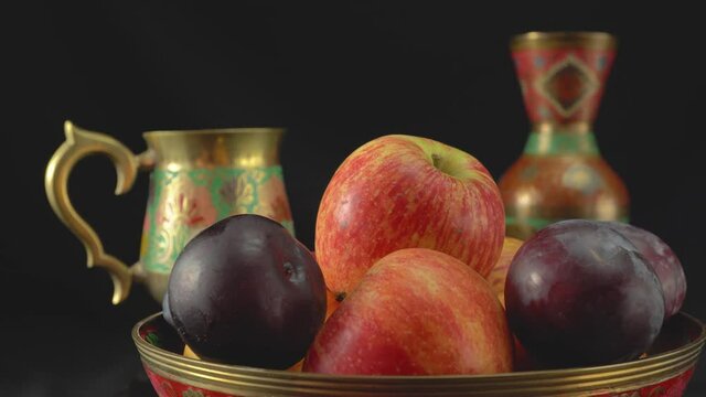 Still life with plums and apples on a dark background