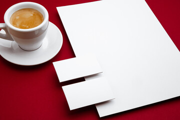 Coffee, blank flyer posters and cards floating above red background. Office styled, modern mockup for advertising, image or text. Blank white copyspace for design, business and finance concept.