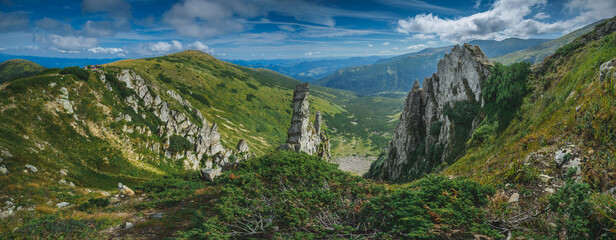 Fototapeta na wymiar Summer panoramic view during the day on a mountain range with rocky formations.