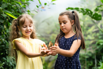 two little girls with butterflies in a greenhouse