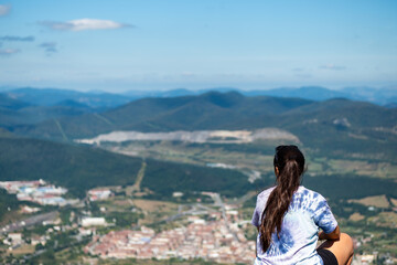 Chica sentada de espaldas con una cola larga observando el paisaje