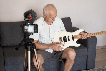 Senior guitarist making video lessons and tutorials for internet vlog website classes.
