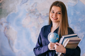 woman holding planet earth globe in hand and books near world ma