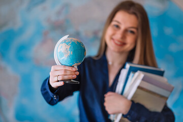 Smiling young student girl hold in hands globe and books