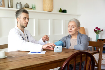 Obraz premium Doctor visit old lady patient measure. Regular checkup of elderly woman by medical digital tonometer at home. 