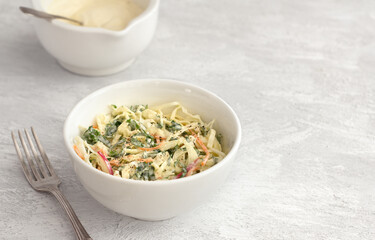 Homemade healthy coleslaw salad with kale in white bowl on gray textured background, space