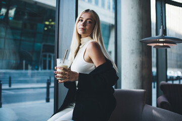 Blond elegant woman having coffee break in urban restaurant