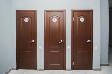 Toilet and shower room for men and women in office. Interior with three brown closed doors.
