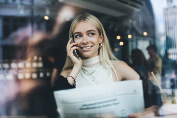 Smiling female with newspaper speaking on phone