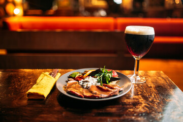 Meat and vegetables dish with a glass of dark beer