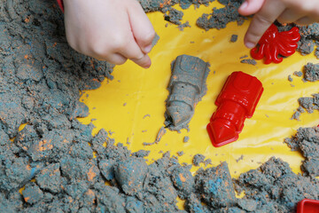 child builds towers from kinetic sand