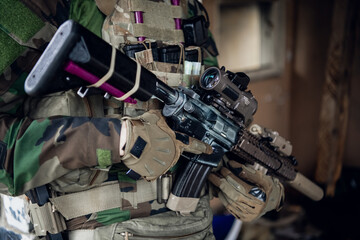 Weapons close-up on a military man standing inside the building and waiting for command.