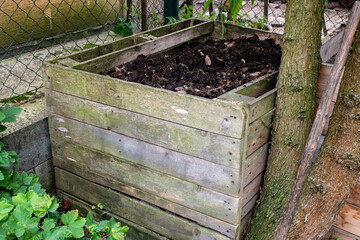 Homemade wooden compost bin in the garden. Recycling organic biodegradable material and household...