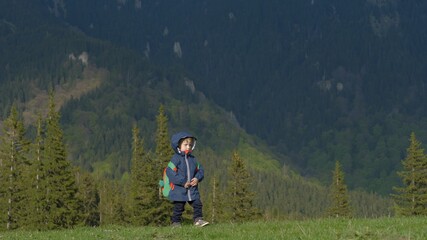 Fototapeta na wymiar Funny little child with backpack travel in mountain, boy let down heavy luggage