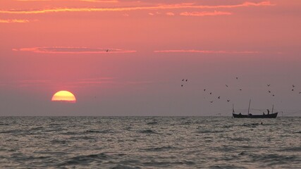 Sun rising over sea, isolated fishing boat floating, beautiful seascape