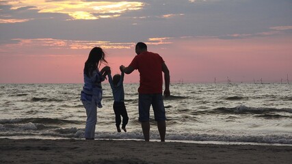 Beach sunset silhouette of happy family having fun on vacation